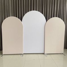 three white and pink booths are lined up against a wall with drapes on it