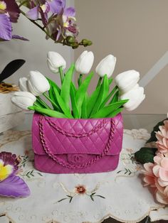 a pink purse with flowers in it sitting on a table