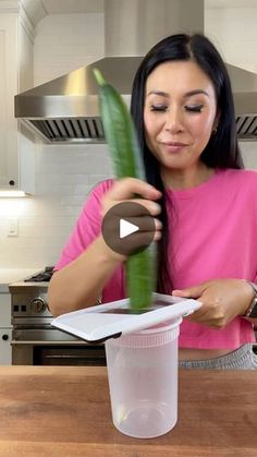 a woman in a pink shirt is holding a green plant