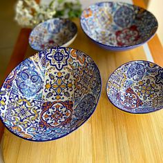 three blue and white bowls sitting on top of a wooden table