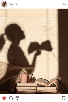 the shadow of a person holding a flower next to books