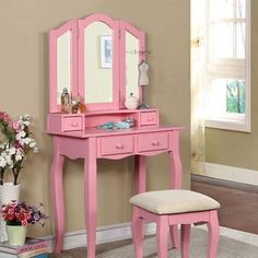 a pink dressing table with mirror and stool