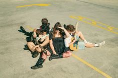 four young people sitting on the ground with guitars in their hands and one holding a guitar