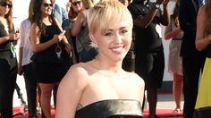 a woman in a strapless black dress posing for the camera on a red carpet