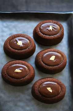 chocolate cookies on a baking sheet with gold foil in the middle and frosting on top