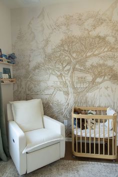 a baby's room with a tree mural on the wall and a crib