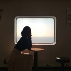 a woman sitting at a table looking out the window