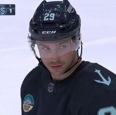 the hockey player is wearing a helmet and looking to his left with one eye open