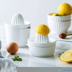 three white bowls with lemons and an egg in them on top of a counter