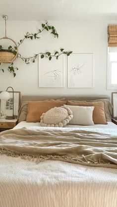 a bed with two pictures hanging on the wall above it and some pillows in front of it