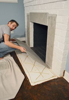 a man laying on the floor in front of a fireplace with a sheet over it