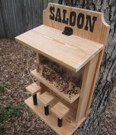 a bird feeder made out of wood with the word saloon on it's side