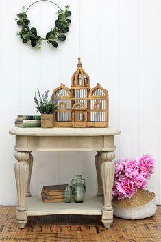 a birdcage is sitting on top of a table next to some books and flowers