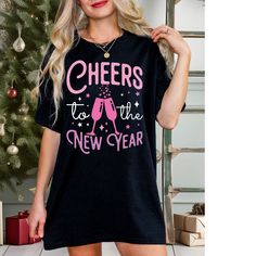 "🥂 Cheers to the New Year Shirt: Toasting Style and Celebration! 🎉 🎊  \"Cheers to the New Year\" graphic, this tee is a perfect blend of style & celebration, making it the ideal choice for counting down to midnight or raising a toast with loved ones. Pair it effortlessly with jeans or leggings and an oversize cardigan.  🥂 Premium Comfort:  Ensures a comfortable fit, perfect for intimate gatherings to lively parties, it's designed to complement your style for all your New Year festivities. 🎁 Perfect Gift Idea: Looking for a thoughtful and stylish gift to usher in the New Year? This tee is a great choice for spreading joy and positivity to friends, family, or yourself. New Year 2024 Shirt, Cheers to the New Year, Girls New Year Trip Tshirt, New Years Eve Party Shirt, Matching New Year C Cheers To The New Year, New Years Eve Shirt, Oversize Cardigan, Travel Tshirt, New Years Shirts, Year 2024, Oversized Cardigan, New Years Eve Party, Stylish Gifts