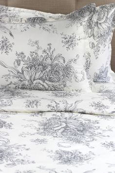 an image of a bed with white and grey floral print on the pillowcases