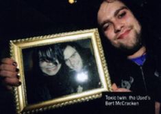 a man holding up a framed photo with a woman's face