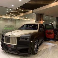 a black and white car is parked in front of a red truck at a showroom