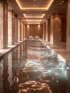 an indoor swimming pool surrounded by columns and flooring with water running down it's sides