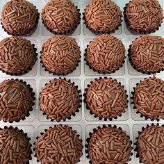 twelve chocolate cupcakes in a box with sprinkles on the top