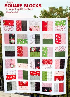 a quilt made with squares and flowers on top of a wooden bench in front of trees