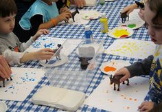 several children are sitting at a table painting