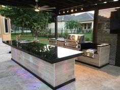 an outdoor kitchen with black counter tops and stainless steel grilling equipment on the island