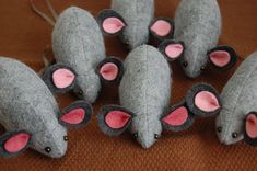 several gray mice with pink ears sitting on a brown cloth covered surface, all facing the same direction