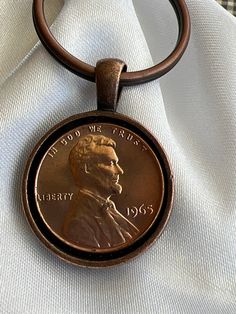 a close up of a coin on a key chain with a white cloth in the background