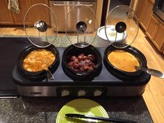 three different types of food are in bowls on the stove top with spoons and plates