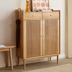 a wooden cabinet sitting next to a wall with pictures on top of it and an umbrella in the corner