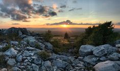 the sun is setting over some rocks and trees