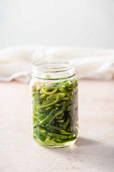 a jar filled with green beans sitting on top of a table