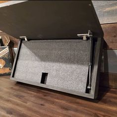 an open briefcase sitting on top of a wooden floor next to a box filled with books