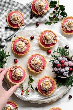 a platter filled with mini pies covered in frosting and cranberries