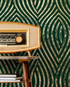 an old radio sitting on top of a wooden table next to a green wallpaper