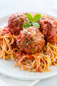 spaghetti and meatballs on a white plate with basil garnished in parmesan sauce