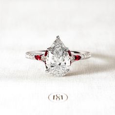 a close up of a ring with a diamond and red stones on the band,