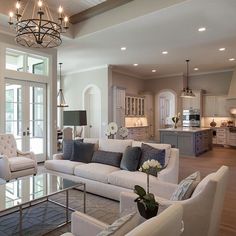 a living room filled with furniture and a chandelier hanging from the ceiling above it