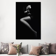 a black and white photo of a woman's body on a wall above a couch