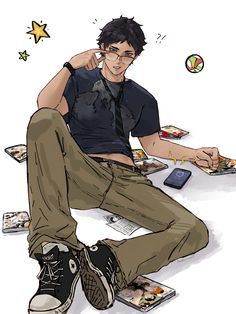 a young man sitting on the ground with his cell phone to his ear and other items around him