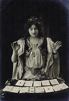 an old photo of a woman sitting at a table with cards in front of her