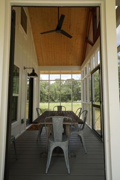 a table and chairs on a porch with a ceiling fan in the middle of it