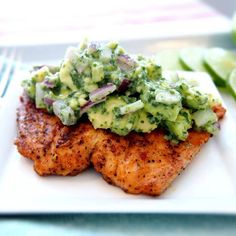 a white plate topped with meat covered in broccoli and cucumber sauce