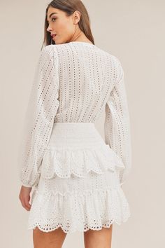 Embrace your feminine side with our White Lace Mini Dress with Ruffle Tiers in elegant white. This stunning mini dress features long sleeves, ruffle tiers, and a delicate front cutout detail, combining elegance with a flirty touch. Crafted from 100% cotton, the lace eyelet fabric adds a touch of sophistication to your look. The mini length showcases your legs and is perfect for a night out or any special occasion. This dress is designed to make a statement and turn heads wherever you go. Experie White Long Sleeve Feminine Mini Dress, Long Sleeve White Feminine Mini Dress, Elegant Tiered Skirt Mini Dress For Spring, Chic White Tiered Mini Dress, White Feminine Mini Dress With Ruffled Skirt, White Long Sleeve Dress With Ruffled Skirt, Elegant White Mini Dress With Tiered Skirt, Spring Long Sleeve Mini Dress With Ruffles, Spring Mini Dress With Ruffles And Long Sleeves