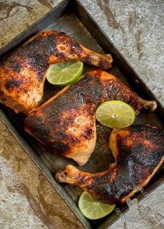 chicken with limes and lemon slices on a baking sheet