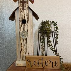 a birdhouse with a sign that says restore next to it is a potted plant