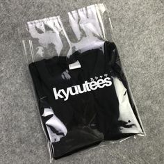 two black and white shirts sitting on top of a floor next to each other in plastic bags