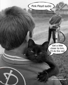 a black cat sitting on the back of a man's shoulder while another person rides a bicycle behind him