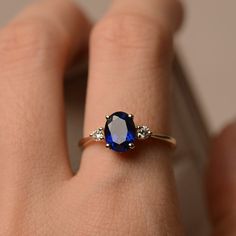 a woman's hand with a blue and white diamond ring on her left hand