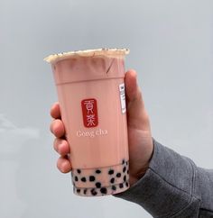 a person holding up a pink drink with black dots on it's wrapper